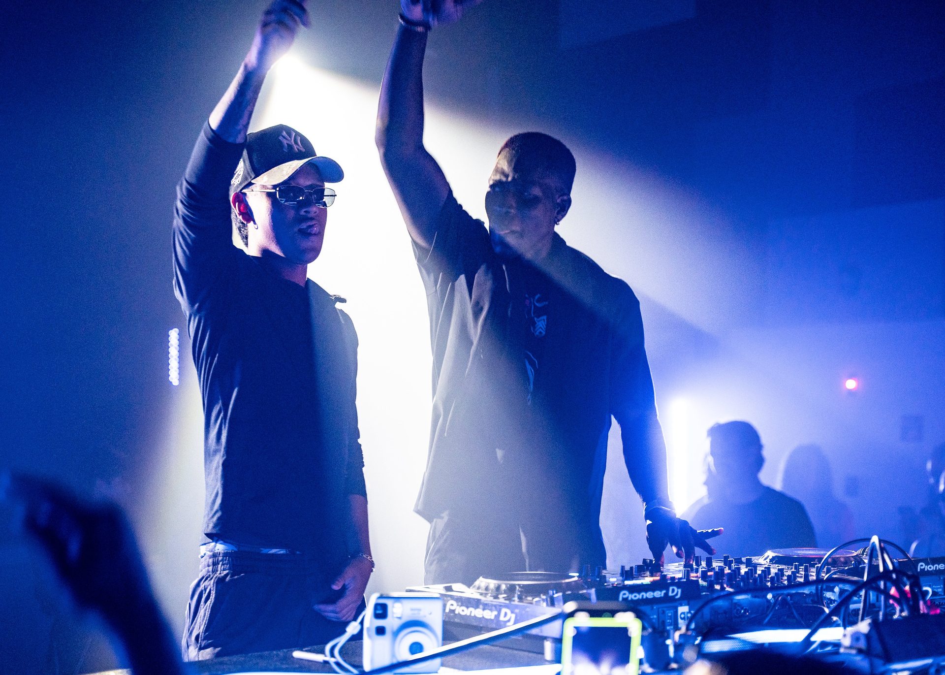 Two DJs on stage under blue lights