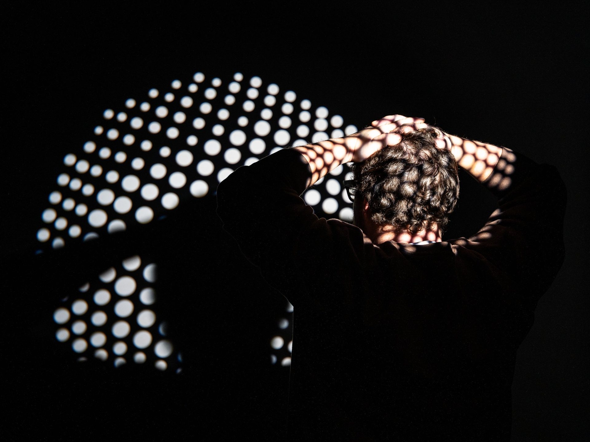 Creative studio portrait with a dotted gobo light pattern on a black backdrop in Saskatoon