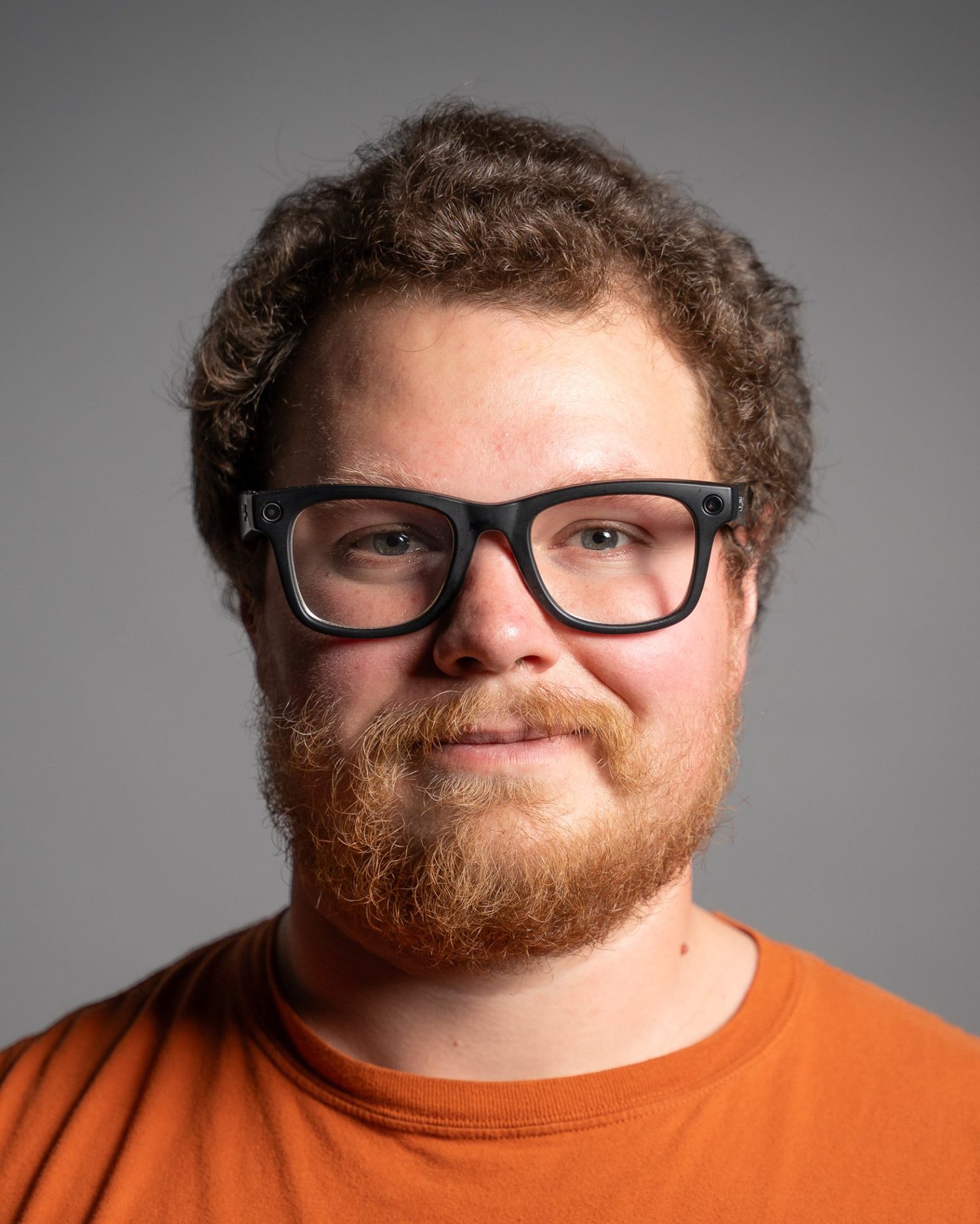 Studio headshot of a smiling man with glasses on a grey backdrop, Saskatoon headshot photographer