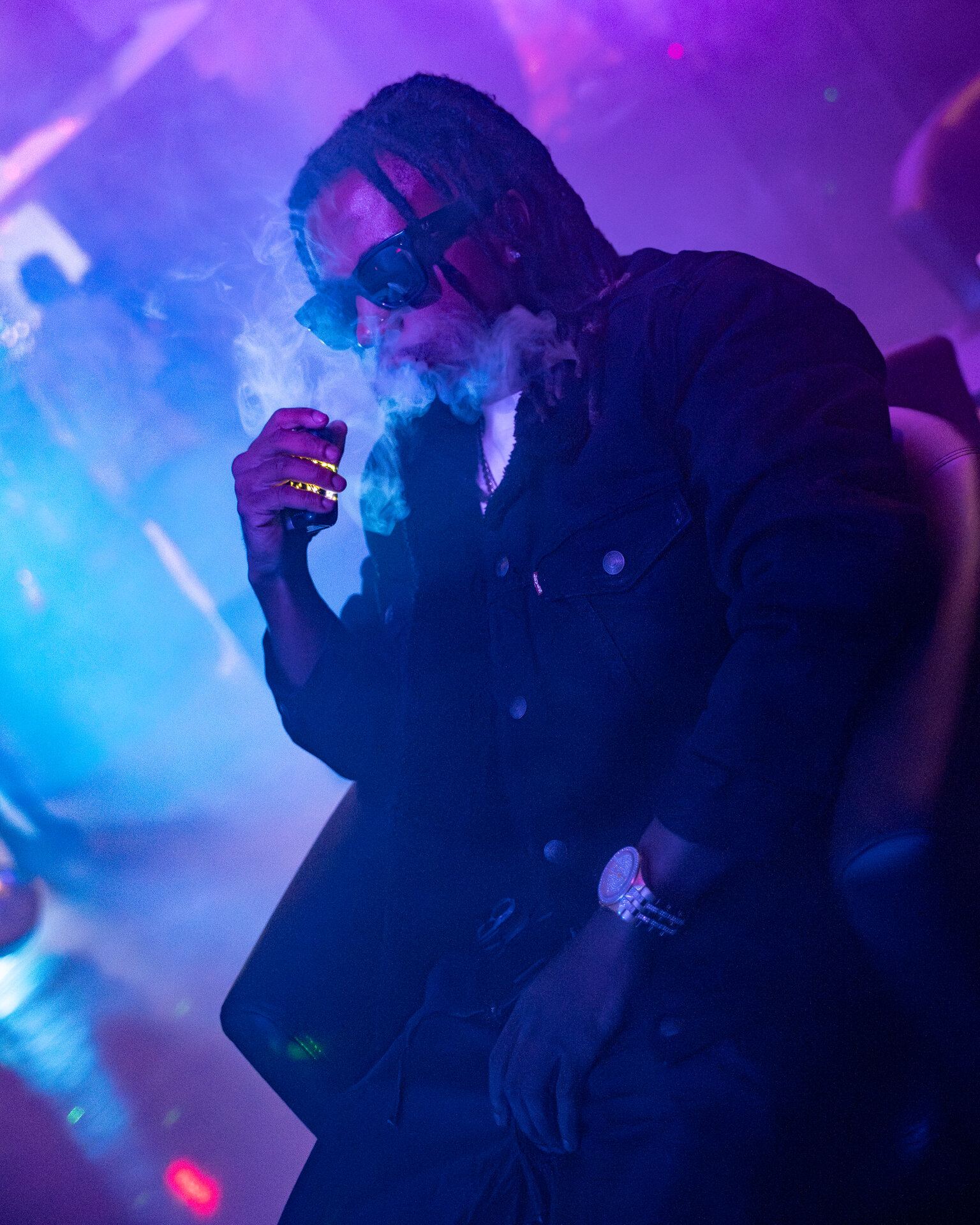 Man exhaling smoke under purple club lighting in Saskatoon