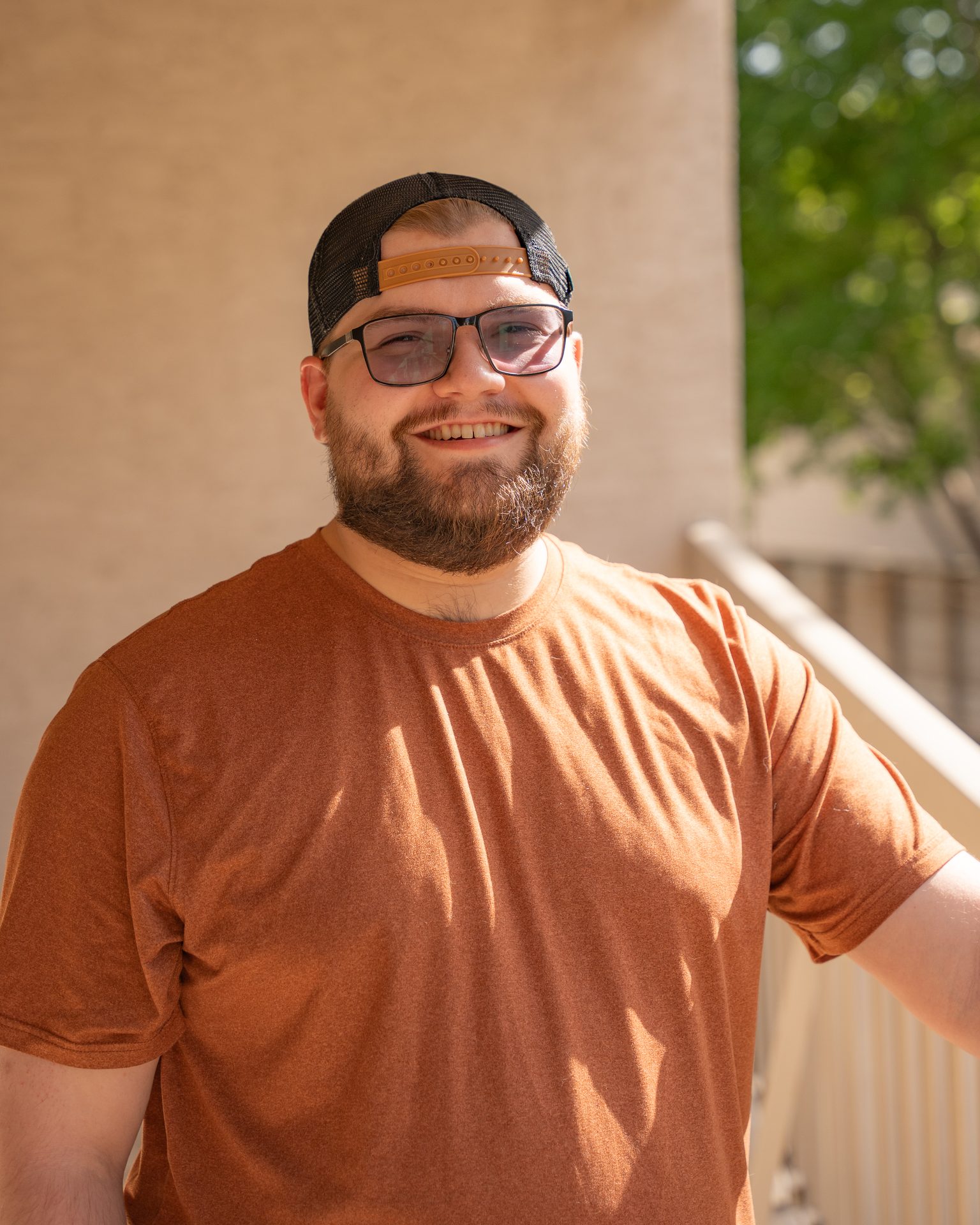 Smiling man in a backwards cap and orange tee, outdoor portrait in Saskatoon