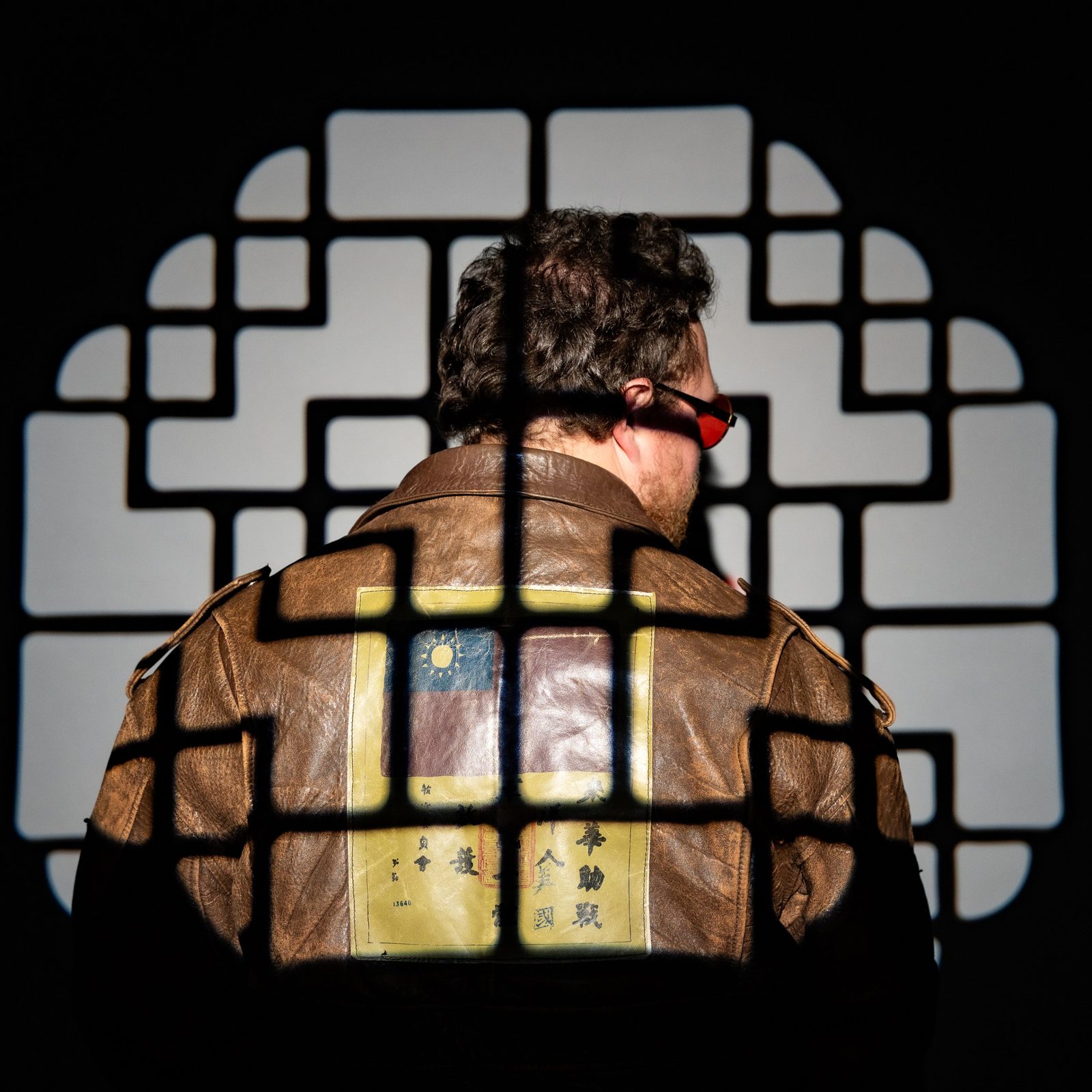 Man in a vintage leather flight jacket lit through a lattice gobo, Saskatoon studio portrait